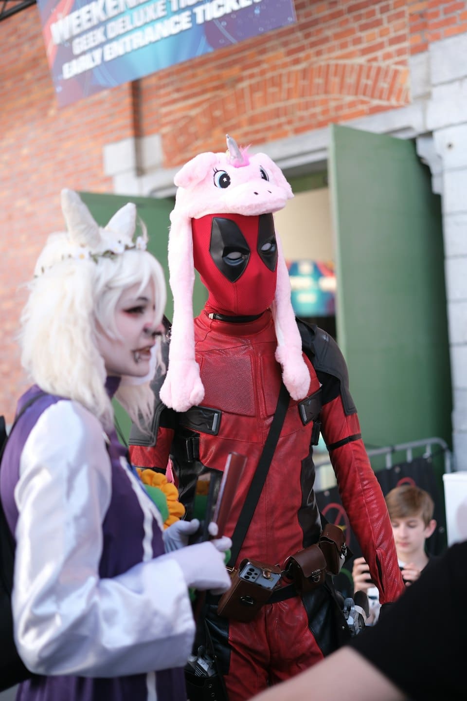 Deadpool con un cappello da unicorno accanto a un cosplayer fantasy di elfo.