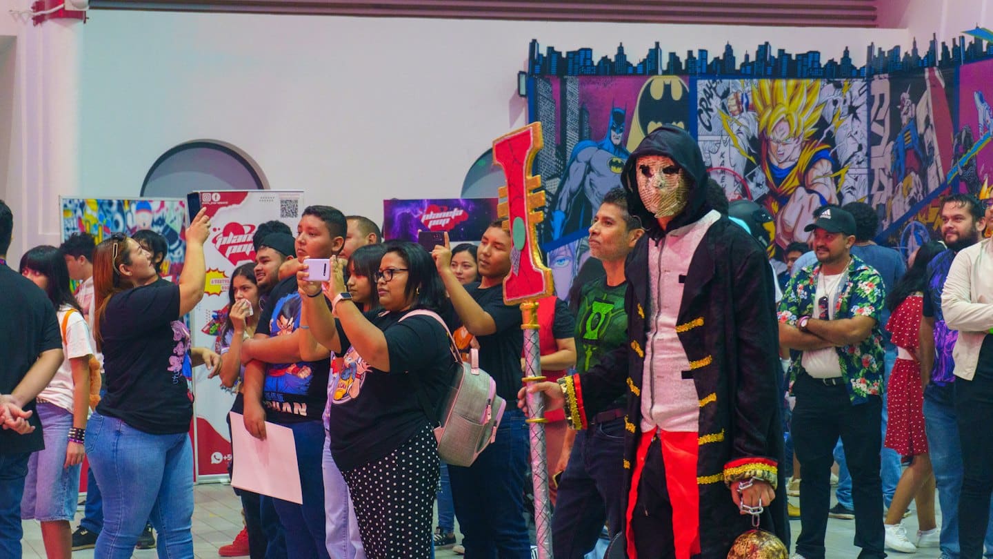Cosplayer con bastone a una convention di fumetti affollata al chiuso.