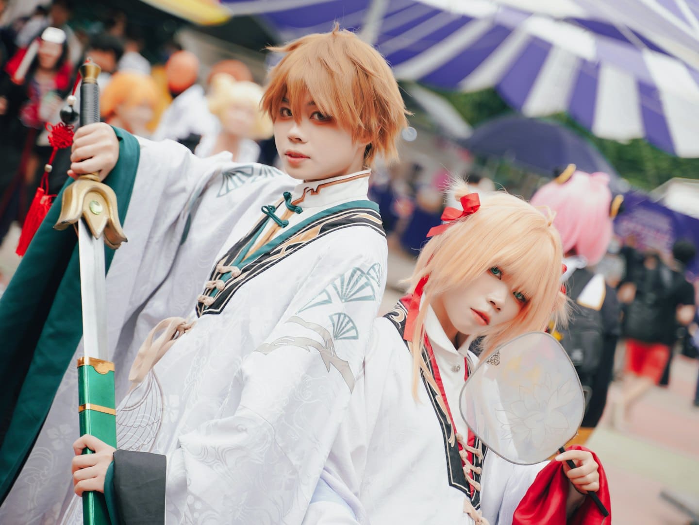 Due persone in costumi cosplay tradizionali posano a un festival all'aperto.